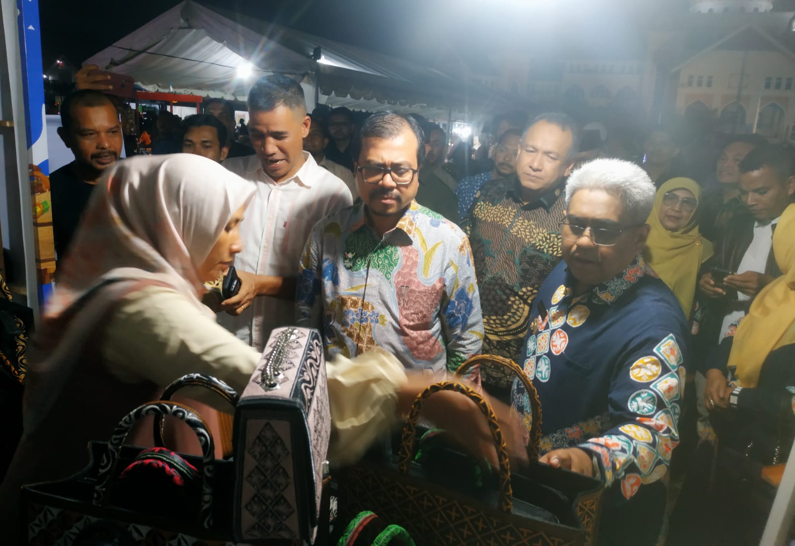 Pj. Sekda Aceh Azwardi dan Pj. Bupati Aceh Utara Mahyuzar melihat tas bordir produk UMKM asal Krueng Mane, Aceh Utara, yang dipamerkan di stan Bazar Produk UMKM Aceh di Lapangan Landing, Lhoksukon, Aceh Utara, Jumat, 5 Juli 2024, malam. Foto for Line1.News