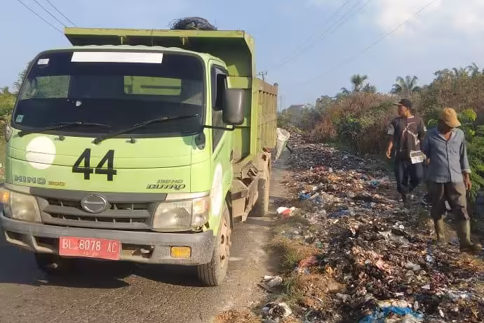 Petugas kebersihan DLHK Aceh Utara mengangkut tumpukan sampah di pinggir jalan. Foto: Istimewa