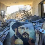 Potret pemimpin Hizbullah Hassan Nasrallah di tengah reruntuhan bangunan di daerah yang menjadi sasaran serangan udara Israel di Saksakiyeh, Lebanon, pada 26 September 2024. Foto: Getty Images