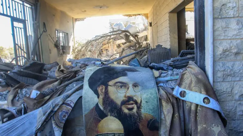 Potret pemimpin Hizbullah Hassan Nasrallah di tengah reruntuhan bangunan di daerah yang menjadi sasaran serangan udara Israel di Saksakiyeh, Lebanon, pada 26 September 2024. Foto: Getty Images