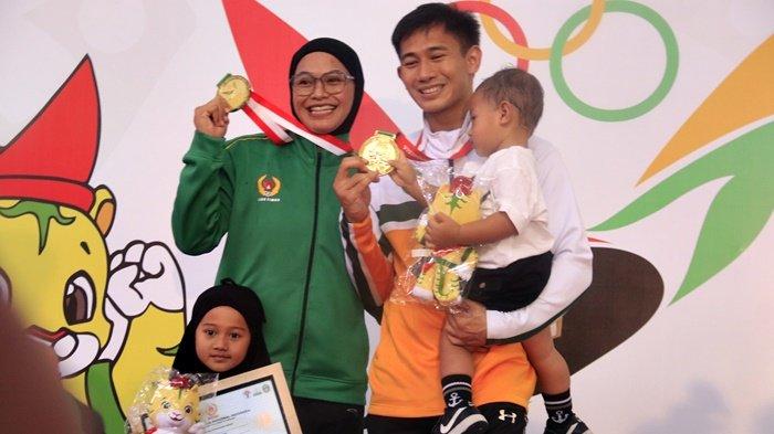 Ikbal Candra Pratama (Kaltim) dan Sarah Tria Monita (Jawa Timur) bersama anak-anak mereka usai meraih emas pencak silat PON XXI Aceh-Sumut di GOR Veteran, Medan, Sumatera Utara, Jumat (13/9/2024). Keduanya berhasil mengawinkan emas pencak silat sebanyak 5 kali. Foto: Tribunnews.com