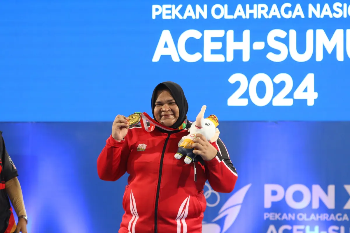 Amel memamerkan medali emas yang diraihnya di kelas +87 kilogram putri. Foto: Herlinurdiansyah/Humas KONI Aceh