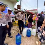 Kasatlantas Polres Lhokseumawe, AKP M Abdhi Hendriyatna melihat penyaluran air bersih untuk warga Dusun IV Pusong Baru, Lhokseumawe. Foto: Line1.News/Fajar