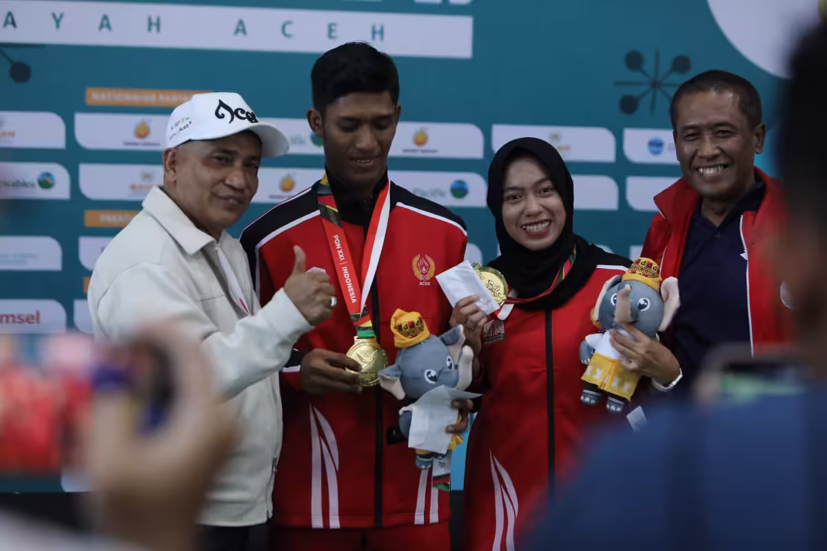 Ketua Umum Koni Aceh Kamaruddin Abu Bakar usai mengalungkan medali kepada pasangan ganda campuran soft tenis Aceh, Maulidan Laksana dan Ella Faradilla, Minggu, 15 September 2024. Foto: Istimewa