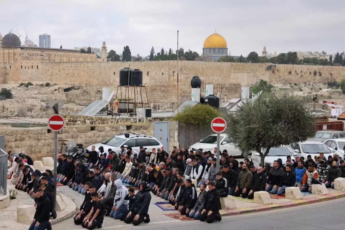 Muslim Palestina salat Jumat di Yerusalem timur dengan latar belakang Masjid Al-Aqsa, Desember 2023. Foto: AFP