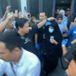 Tim Satreskrim Polres Lhokseumawe membawa terduga pelaku berinisial Wl (memakai masker) keluar dari tempat kejadian setelah menjalani pra-rekonstruksi kasus pembunuhan Laksmiwati Anggraini, Selasa, 8 Oktober 2024, sore. Foto: Line1.News/Fajar