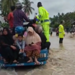 Personel Satlantas Polres Pidie membantu warga melintas banjir di kawasan Padang Tiji