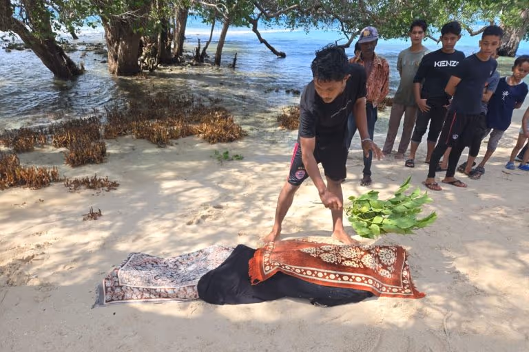 Warga menutupi jenazah pria yang ditemukan di lokasi wisata Pantai Pasir Putih Krueng Raya