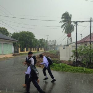 Anak sekolah berlarian saat hujan di Gampong Jawa Idi Rayeuk