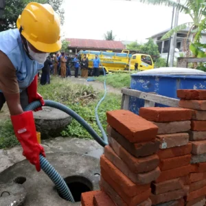 Petugas menyedot tinja dari sebuah septi tank di rumah warga