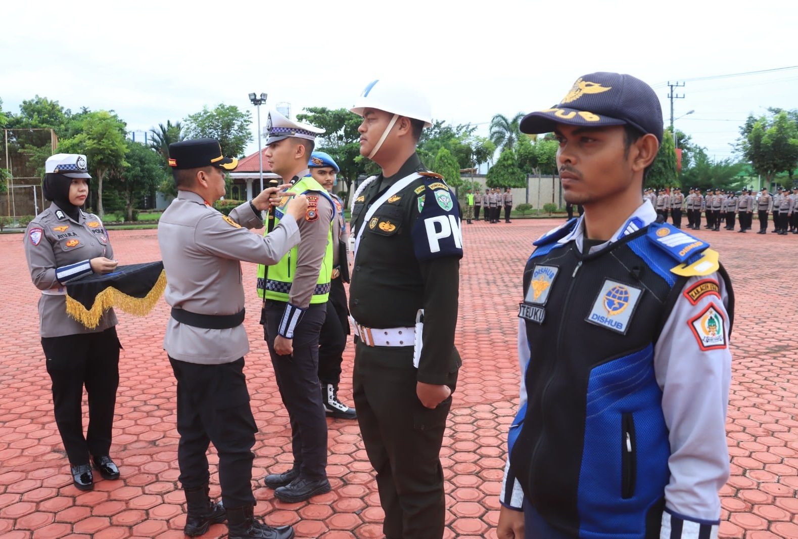 Kapolres Aceh Utara AKBP Trie Aprianto menyematkan pita operasi kepada perwakilan personel TNI, Polri, dan Dishub dalam Apel Operasi Patuh Seulawah 2026.