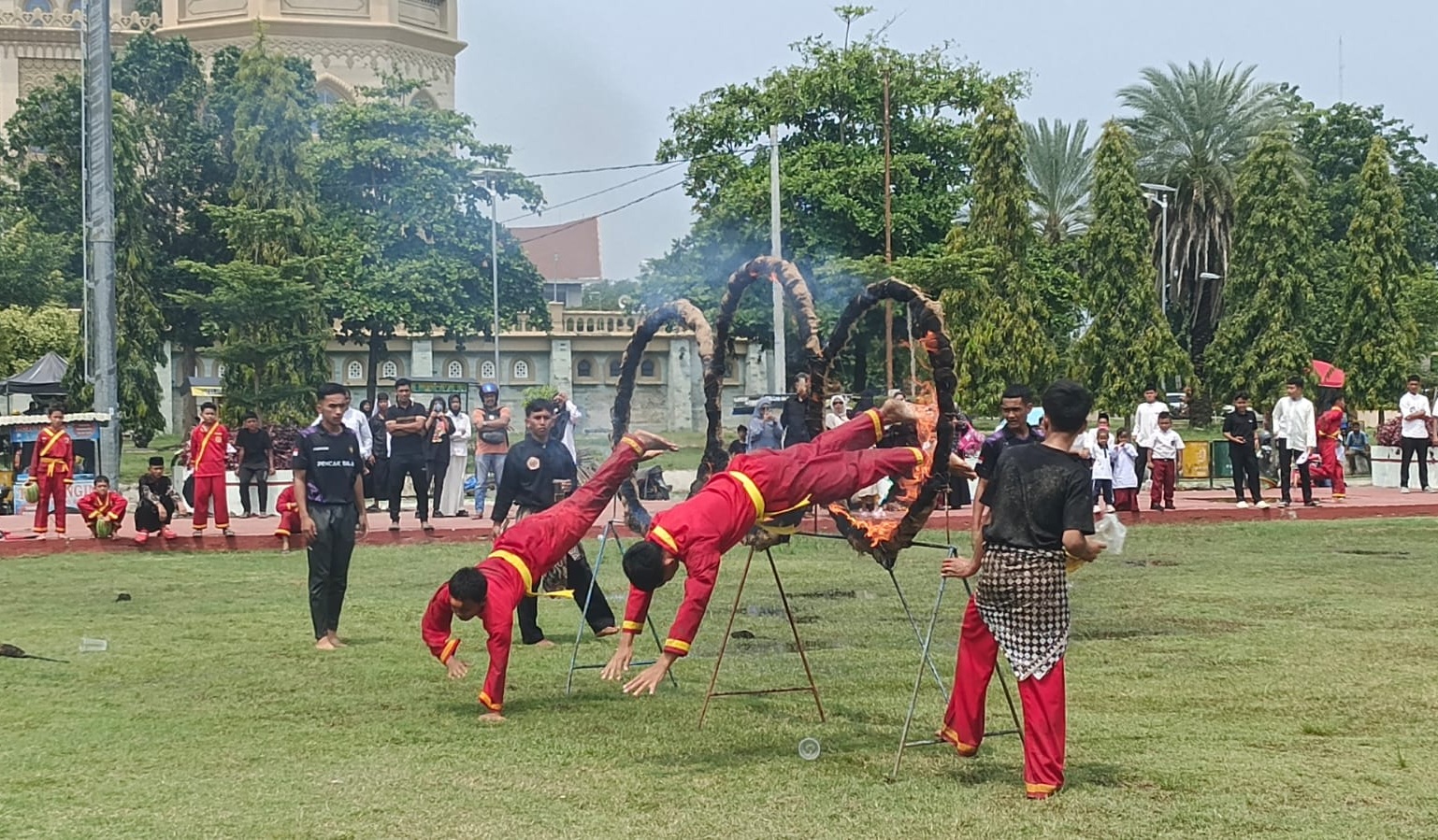 Dua orang santri berseragam merah khas Tapak Suci melakukan atraksi menegangkan melompati lingkaran yang membara oleh api di tengah Lapangan Hiraq Lhokseumawe