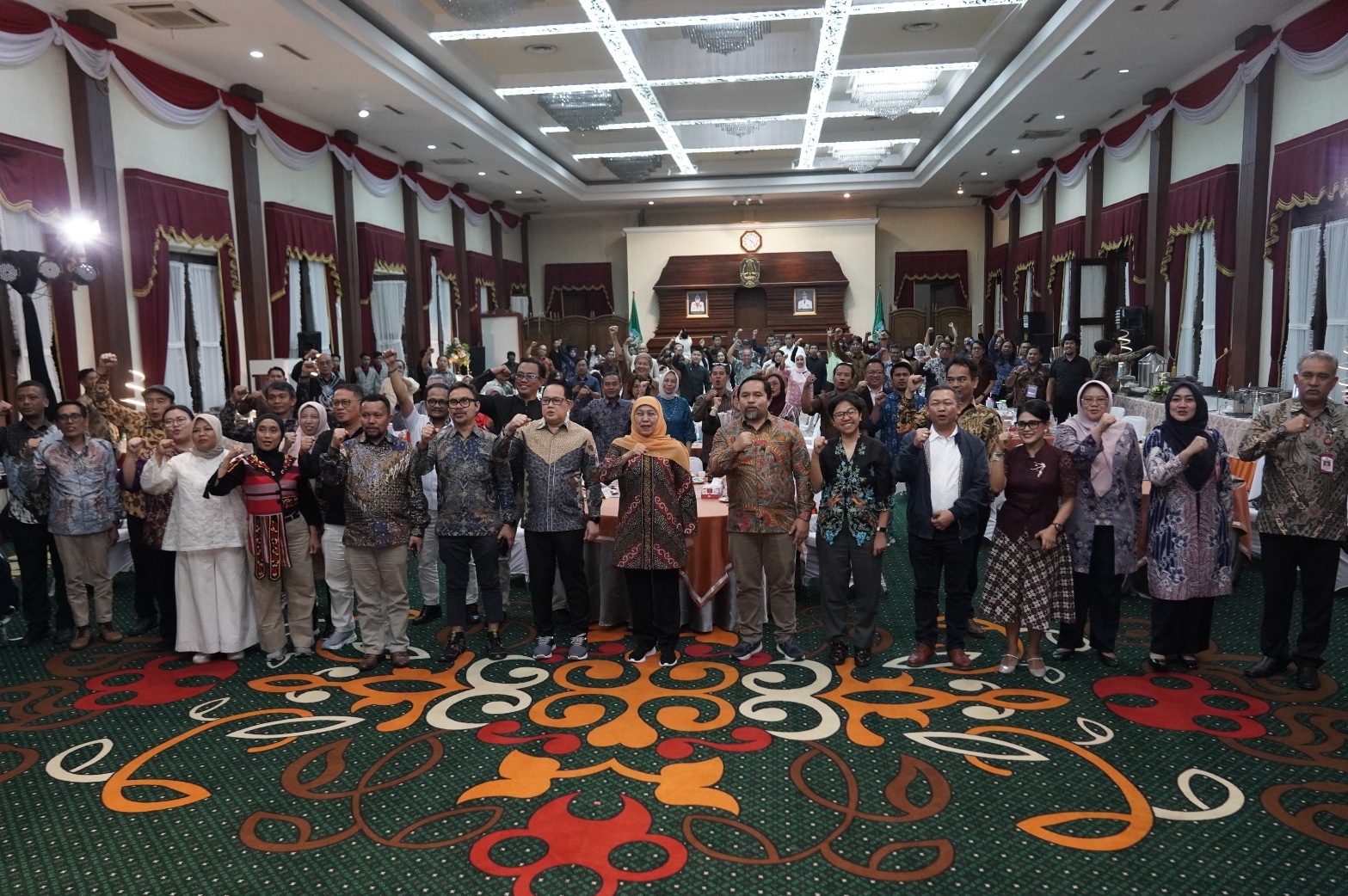Gubernur Jawa Timur bersama Ketua Umum AMSI dan belasan perwakilan pimpinan media siber berfoto bersama sambil mengepalkan tangan di dalam aula Gedung Negara Grahadi.