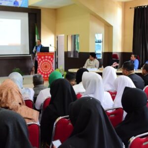 Barisan tenaga kesehatan dan dokter RSUD Datu Beru mengenakan seragam putih dan jilbab hitam sedang duduk menyimak pemaparan materi survei akreditasi dari proyektor di aula.