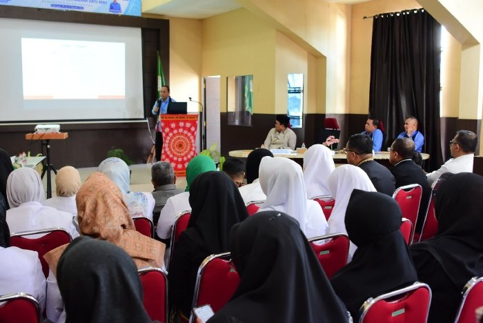 Barisan tenaga kesehatan dan dokter RSUD Datu Beru mengenakan seragam putih dan jilbab hitam sedang duduk menyimak pemaparan materi survei akreditasi dari proyektor di aula.