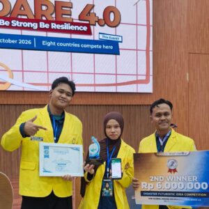 Tiga mahasiswa PNL memakai almamater kuning tersenyum bangga di atas panggung sambil memegang sertifikat, piala, handphone JAGA App, dan papan hadiah Juara 2 USK Global Award on Disaster Resilience 4.0.