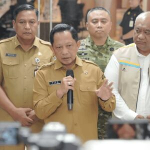 Mendagri Muhammad Tito Karnavian memberikan keterangan pers kepada media menggunakan mikrofon, didampingi jajaran pejabat