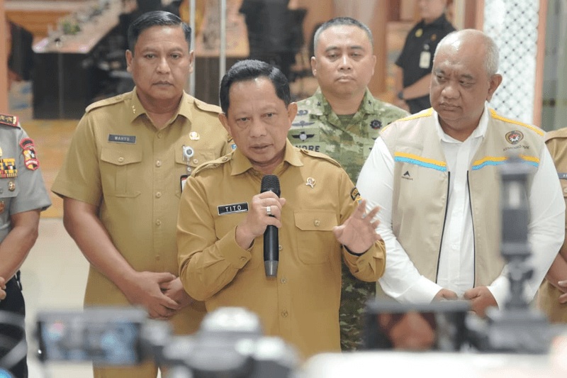 Mendagri Muhammad Tito Karnavian memberikan keterangan pers kepada media menggunakan mikrofon, didampingi jajaran pejabat