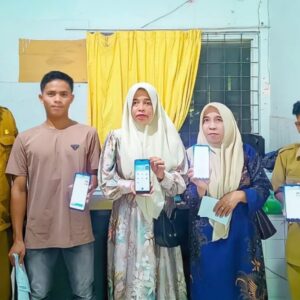 Tiga warga dan petugas Disdukcapil Aceh Utara berdiri bersama sambil tersenyum memperlihatkan layar handphone aplikasi Identitas Kependudukan Digital