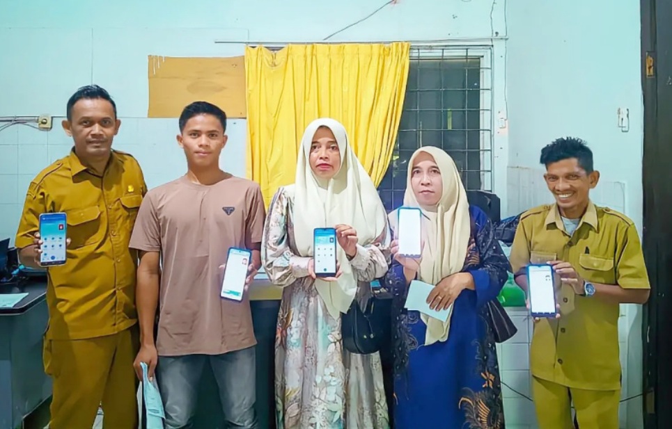 Tiga warga dan petugas Disdukcapil Aceh Utara berdiri bersama sambil tersenyum memperlihatkan layar handphone aplikasi Identitas Kependudukan Digital