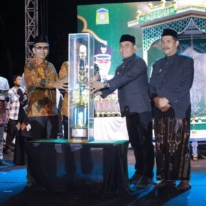 Bupati Aceh Besar Muharram Idris menyerahkan piala bergilir juara umum MTQ ke-35 kepada Camat Peukan Bada Salamuddin ZM di panggung utama Lapangan Bung Cala Kuta Baro.