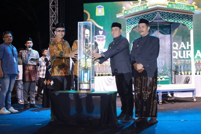 Bupati Aceh Besar Muharram Idris menyerahkan piala bergilir juara umum MTQ ke-35 kepada Camat Peukan Bada Salamuddin ZM di panggung utama Lapangan Bung Cala Kuta Baro.