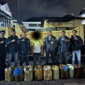 Sejumlah personel Satreskrim Polresta Banda Aceh berfoto bersama seorang pria berkaus kuning di depan dump truck, dengan deretan jerigen solar berjajar di bagian depan.