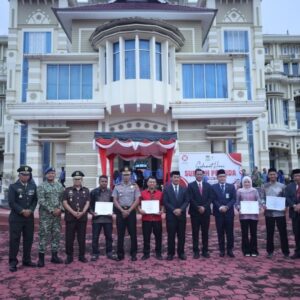 Jajaran unsur Forkopimda Aceh Besar berdiri berjejer melakukan foto bersama dengan empat pemuda penerima penghargaan Pemuda Inovatif di halaman upacara.