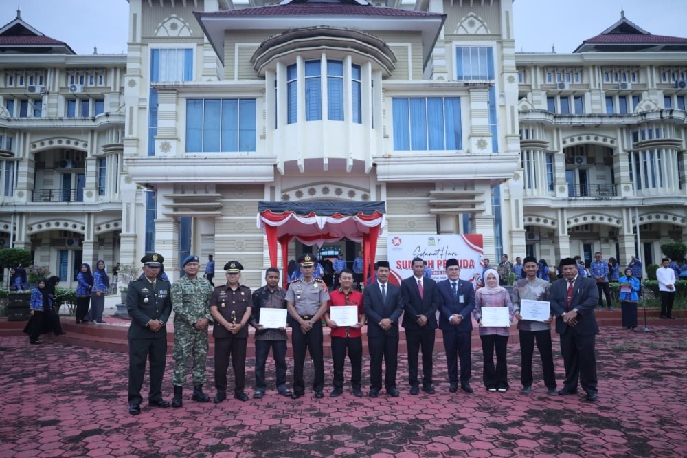 Jajaran unsur Forkopimda Aceh Besar berdiri berjejer melakukan foto bersama dengan empat pemuda penerima penghargaan Pemuda Inovatif di halaman upacara.