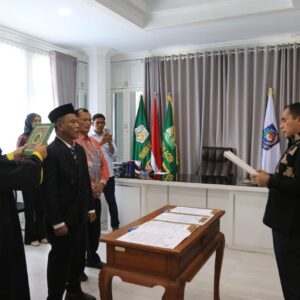 Wali Kota Lhokseumawe Sayuti Abubakar saat membacakan naskah sumpah pelantikan kepada T. Sofianus yang berdiri didampingi seorang rohaniwan pembawa Al-Qur'an di ruang kerja.