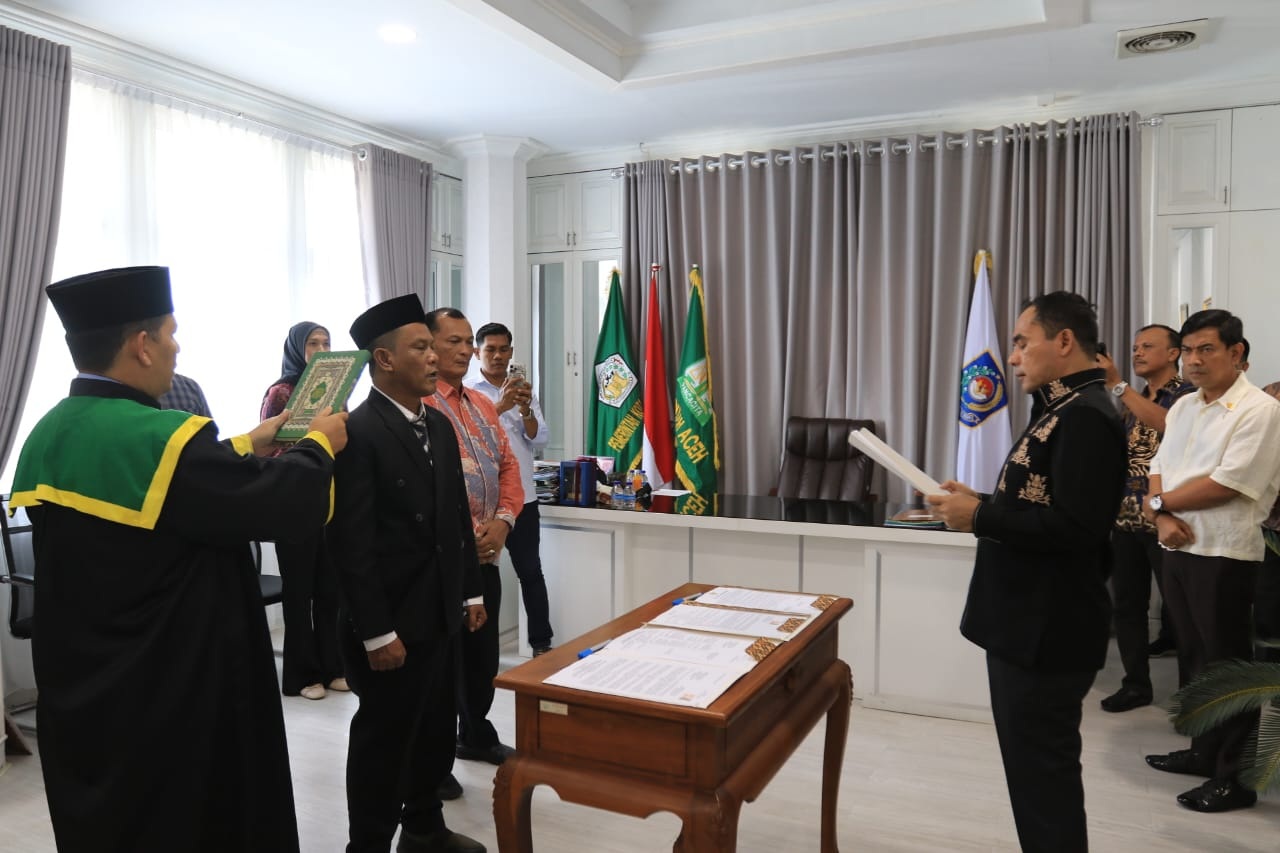 Wali Kota Lhokseumawe Sayuti Abubakar saat membacakan naskah sumpah pelantikan kepada T. Sofianus yang berdiri didampingi seorang rohaniwan pembawa Al-Qur'an di ruang kerja.