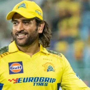 Mantan kapten tim kriket India MS Dhoni tersenyum mengenakan seragam kuning dan topi kuning bermotif loreng khas tim Chennai Super Kings dalam sebuah pertandingan.